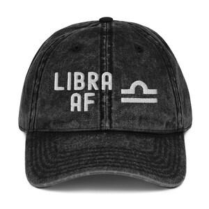May include: Black vintage washed denim baseball cap with white embroidered text "LIBRA AF" and the Libra zodiac symbol.