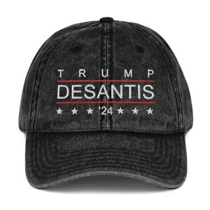 Puede incluir: Gorra de béisbol negra de estilo vintage con el texto bordado en blanco "TRUMP DESANTIS '24" y cinco estrellas blancas.