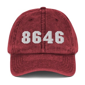 May include: A red vintage washed cotton baseball cap with white embroidered text that reads "8646".