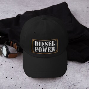 May include: A black baseball cap with a brown patch that says "Diesel Power" in white letters.