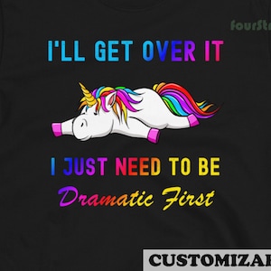 Könnte beinhalten: Schwarzes T-Shirt mit einem Regenbogen-Einhorn-Motiv und dem Text "Ich werde darüber hinwegkommen, ich muss nur erst mal dramatisch sein".