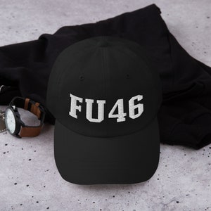Puede incluir: Gorra de béisbol negra con un logotipo bordado en blanco que dice "FU46".