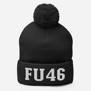 Puede incluir: Gorro negro con pompón blanco y el texto "FU46" en blanco en el puño.