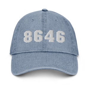 Puede incluir: Una gorra de b&eacute;isbol de mezclilla azul con texto blanco bordado que dice "8646".