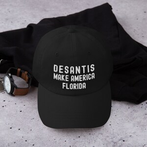 Puede incluir: Gorra de béisbol negra con texto bordado en blanco que dice "DESANTIS MAKE AMERICA FLORIDA".