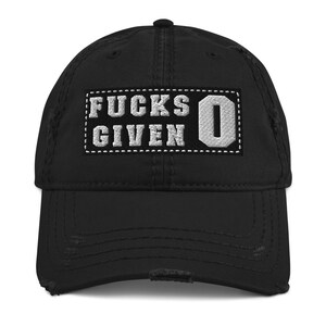 Könnte beinhalten: Schwarze, abgenutzte Baseballkappe mit einem weißen gestickten Aufnäher, auf dem "F*CKS GIVEN 0" steht.