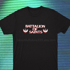 Puede incluir: Camiseta negra con el texto "BATTALION OF SAINTS" en rojo y blanco, con dos gráficos de emblemas estilizados. La URL de la tienda de Etsy beautifulfuture333.etsy.com está impresa debajo.