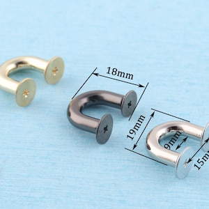 Può includere: Tre anelli a D in metallo con viti. Gli anelli sono larghi 18 mm, alti 19 mm e con un diametro di 15 mm. Gli anelli sono dorati, neri e argentati.