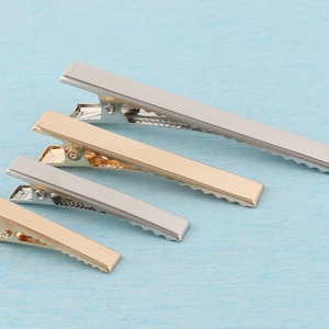 May include: Four hair clips in different sizes. The clips are silver and gold with a textured, wavy design.