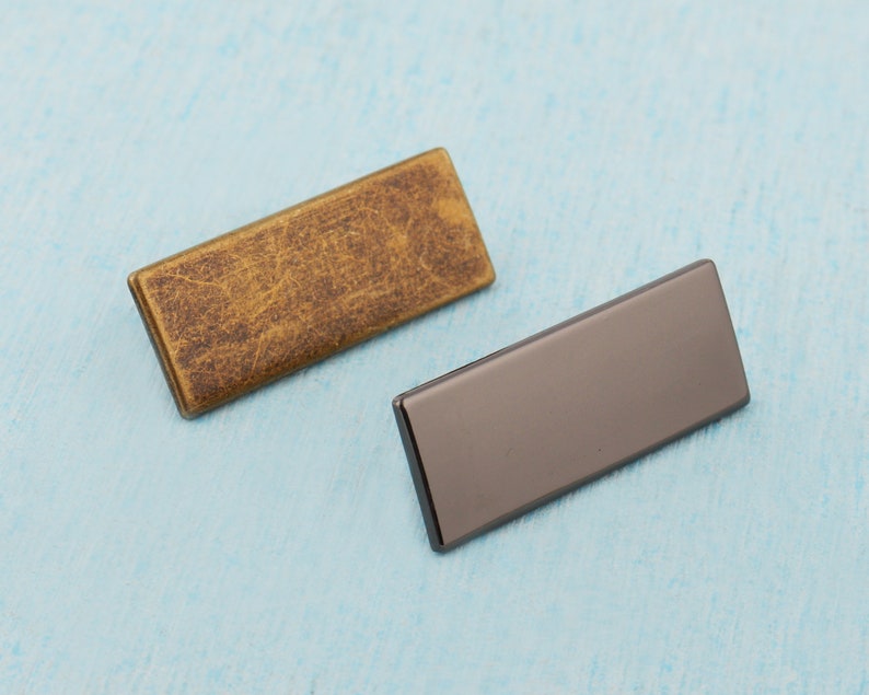 May include: Two rectangular metal plates, one gold and one black, with a textured surface.
