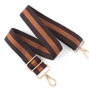 Pode incluir: Uma correia ajust&aacute;vel com listras marrons e bege e ferragens de metal dourado. A correia &eacute; feita de tecido tecido e tem um visual casual.