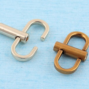 May include: Two metal belt buckle closures, one silver and one antique gold. Both have a D-ring shape with a swiveling bar.