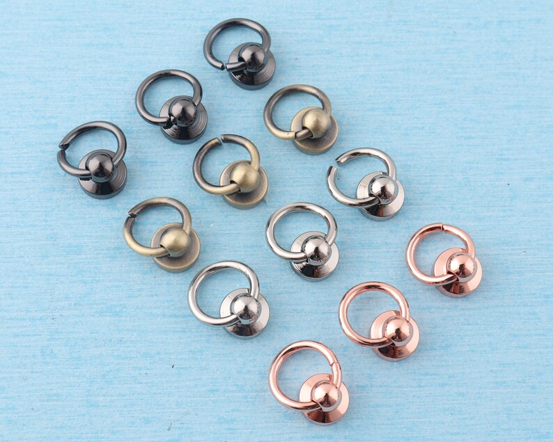 May include: Assortment of metal rings with a ball on top. The rings are in various finishes, including silver, gold, and black.