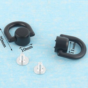 May include: Black metal D-ring hardware with silver screws. The D-rings are 20mm long and 10mm wide. The other D-ring is 11mm long. Ideal for bag making, leathercraft, and other DIY projects.