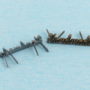 Op de afbeelding: Twee metalen labels met het woord "Handmade" erop. Het label links is zwart en het label rechts is goud.