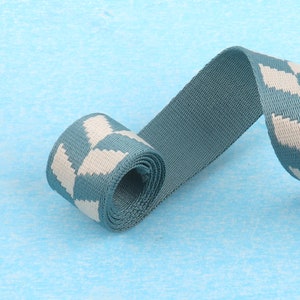 May include: A teal blue and white patterned webbing strap. The strap is rolled up and the pattern is visible on the rolled portion.