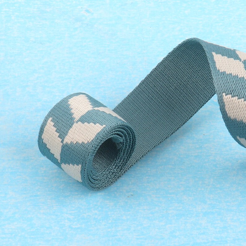 May include: A teal blue and white patterned webbing strap. The strap is rolled up and the pattern is visible on the rolled portion.