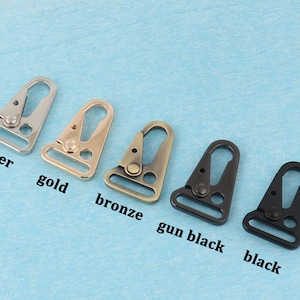 Puede incluir: Una colecci&oacute;n de cierres giratorios met&aacute;licos en varios colores: plata, oro, bronce, negro ca&ntilde;&oacute;n y negro. Cada cierre tiene un gancho triangular y un lazo rectangular. Los colores est&aacute;n etiquetados debajo de cada cierre.