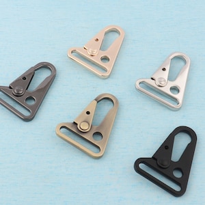 Può includere: Cinque moschettoni girevoli in metallo in diverse finiture: nero, argento, oro, bronzo e nichel. I moschettoni sono di forma triangolare con un gancio a molla.