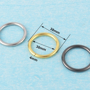May include: Three metal rings, one silver, one gold, and one black. The gold ring is 30mm in diameter and 4mm wide. The silver ring is 38mm in diameter. The black ring is 38mm in diameter.