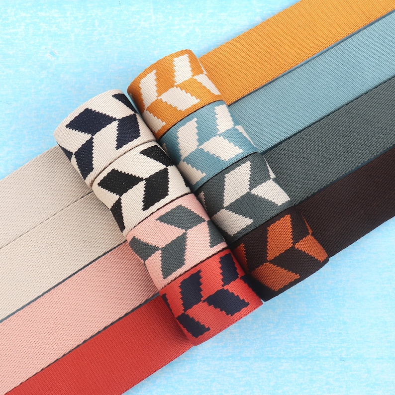 May include: Assortment of eight patterned fabric ribbon trims. The trims feature geometric designs in various colors, including black, white, red, orange, brown, pink, blue, and gray.