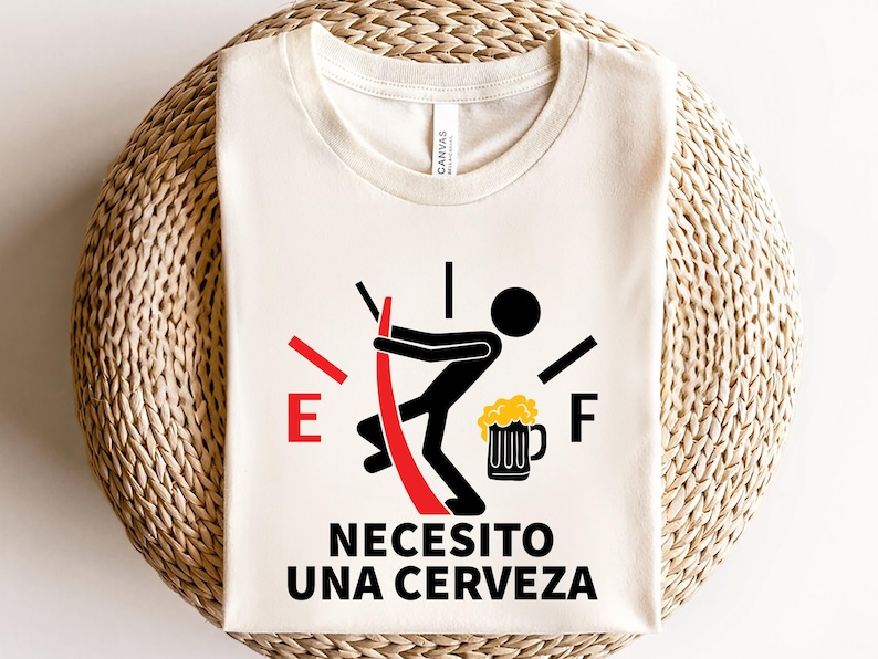 May include: A white t-shirt with a red and black fuel gauge graphic. The gauge is empty and a stick figure is holding a beer mug. The text "Necesito una cerveza" is printed below the graphic.