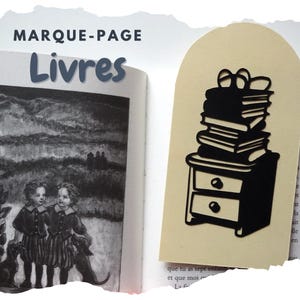 May include: A black bookmark with a stack of books on a nightstand design. The bookmark is placed in a book with a black and white illustration. The French words "MARQUE-PAGE" and "Livres" are at the top.