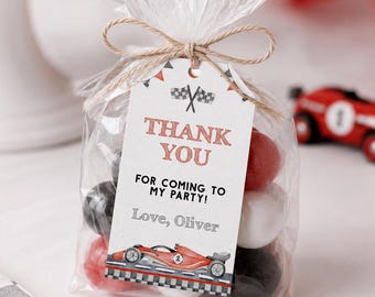 May include: A clear plastic favour bag filled with red, white, and black gumballs, tied with twine and a rectangular tag. The tag features a checkered flag icon, the text "THANK YOU FOR COMING TO MY PARTY! Love, Oliver," and a red race car graphic.