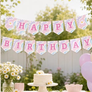 May include: A two-tiered bunting banner featuring the text HAPPY BIRTHDAY in pink letters on pennants with a light blue and lavender wavy pattern and white daisy accents. The banner is displayed above a white cake on a stand and balloons.
