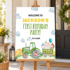 K&ouml;nnte beinhalten: Ein rechteckiges Schild auf einer Holzstaffelei mit dem Text WELCOME TO JACKSON'S FIRST BIRTHDAY PARTY! 15.11.202X. Das Design zeigt einen gr&uuml;nen Traktor, der einen Anh&auml;nger mit Bauernhoftieren in Partyh&uuml;ten und blaue Wolken zieht.