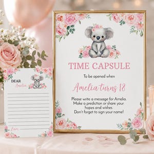 K&ouml;nnte beinhalten: Ein gerahmtes Schild und eine passende Karte mit einer Koala-Illustration und rosa Rosen. Das Schild tr&auml;gt die Aufschrift: TIME CAPSULE, To be opened when Amelia turns 18. Please write a message for Amelia. Make a prediction or share your hopes and wishes.