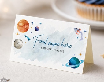 May include: A folded white card featuring a watercolor space theme with planets, a rocket, and stars. The text reads Food name here and EDITABLE TEMPLATE in blue and black ink. The design includes a light blue wash background with celestial elements.