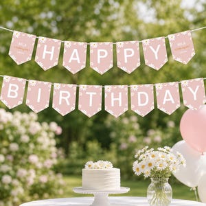 May include: A two-row bunting banner featuring dusty pink pennants with white daisy patterns and large white letters spelling out HAPPY BIRTHDAY. The end pennants include the text Mila is turning one and a date, all strung on white cord.