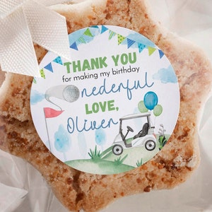 May include: Star-shaped sugar cookies with a golden-brown textured surface, each individually wrapped in clear plastic bags tied with white ribbon. A circular sticker on the front reads: THANK YOU for making my birthday onederful LOVE, Oliver.