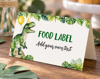 May include: A folded white card with a green dinosaur wearing a yellow party hat and holding a yellow balloon. The card features green tropical leaf illustrations, the text FOOD LABEL in green, and the text Add your own text in black script.