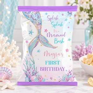 May include: A rectangular snack bag with a purple top and bottom border, featuring a mermaid tail illustration, colorful seashells, and coral. The text reads: Splish Splash It's a Mermaid Bash Mayra's FIRST BIRTHDAY in purple and teal script.