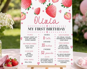 Op de afbeelding: Een wit verjaardagsbord met aquarel aardbeien en roze hartjes. De tekst luidt Olivia My First Birthday, met details zoals 8 tanden, 35 inches, 32 pounds, en categorieën voor favoriete eten, liedjes, boeken en persoonlijkheidskenmerken van het kind.