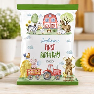May include: A white snack bag with green top and bottom borders featuring a farm theme. Illustrations include a red barn, a cow, a horse, a pig, a tractor, and a windmill. Text reads: Jackson's FIRST BIRTHDAY 10.01.202X. The design includes watercolor style animals and clouds.