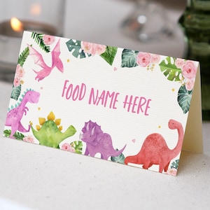 May include: A white card with a pink border and a floral design. The card has a pink banner with the text "FOOD NAME HERE". The card features a watercolour illustration of dinosaurs and tropical leaves.