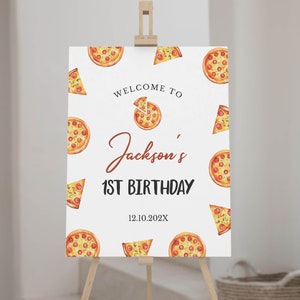 May include: Welcome to Jackson's 1st Birthday sign with a pizza theme. The white sign has a red and brown welcome to Jackson's 1st Birthday text with a pizza slice graphic. The background is covered with pizza slices in various positions.