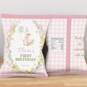 May include: Pink gingham-patterned chip bags for a first birthday celebration. The front features a duck with a party hat and a balloon, surrounded by floral elements. Text reads "Olivia's First Birthday" and the date.