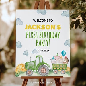 K&ouml;nnte beinhalten: Ein wei&szlig;es rechteckiges Schild mit dem Text WELCOME TO JACKSON'S FIRST BIRTHDAY PARTY! 15.11.202X. Das Design zeigt Aquarellillustrationen von blauen Wolken, einem gr&uuml;nen Traktor und einem Anh&auml;nger mit Nutztieren in Partyh&uuml;ten.