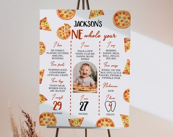 Op de afbeelding: Een witte pizza-thema eerste verjaardag mijlpaalposter met een foto van een babyjongen. De poster bevat de naam van de baby, Jackson, en details over zijn eerste jaar, waaronder zijn gewicht, lengte en favoriete eten, speelgoed en liedjes. De poster is versierd met illustraties van pizzapunten.