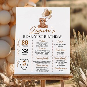 Puede incluir: Un cartel de cumplea&ntilde;os blanco para el primer aniversario de Liam con una ilustraci&oacute;n de un oso pardo y globos, que enumera 12,7 kg, 81,3 cm, 5 dientes, comidas, libros, canciones, juguetes y hitos favoritos en texto marr&oacute;n y negro.