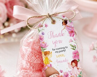 May include: A clear plastic favor bag filled with pink sugar-coated candies, tied with a light pink satin ribbon and a jute twine bow. A rectangular tag features fairy illustrations, pink flowers, mushrooms, and the text Thank you for coming to my party! Love, Amanda.