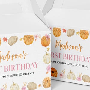 May include: Two white cardboard gable boxes featuring a watercolor design of orange and white pumpkins, pink roses, and autumn leaves. The text reads Madison's FIRST BIRTHDAY THANK YOU FOR CELEBRATING WITH ME! in orange and pink lettering.