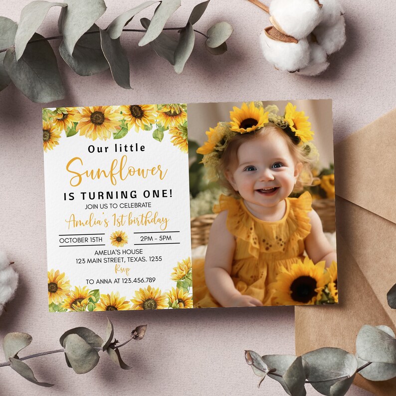 May include: A sunflower-themed first birthday invitation with a photo of a baby girl wearing a sunflower crown. The invitation features a white background with yellow sunflowers and green leaves. The text on the invitation reads "Our little Sunflower is turning one!" and includes details about the birthday party, including the date, time, and location.