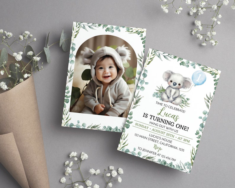 May include: Two rectangular birthday invitation cards featuring a watercolor eucalyptus leaf border. One card displays a photo of a baby in a koala hood. The other card features a koala illustration, a blue balloon with the number one, and text.