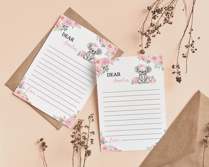 K&ouml;nnte beinhalten: Zwei wei&szlig;e Briefpapierb&ouml;gen mit horizontalen schwarzen Linien, verziert mit einer Aquarellillustration eines grauen Koalas mit rosa Blumenkranz, umgeben von rosa und pfirsichfarbenen Rosen und gr&uuml;nen Bl&auml;ttern. Text: DEAR Amelia und Love.