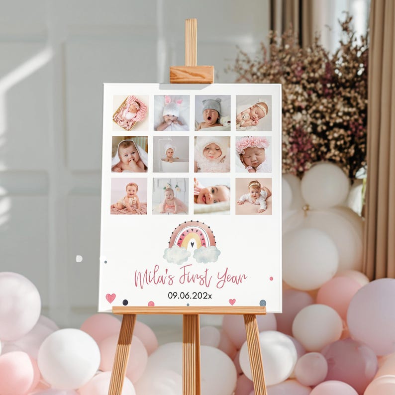 May include: A rectangular sign on a wooden easel featuring a grid of twelve baby photographs, a central watercolour rainbow illustration, and the text "Mila's First Year" followed by the date "09.06.202x" with small pink heart and dot accents.